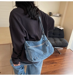 Detailed back view of a blue washed denim hobo bag with stud accents and a zip pocket