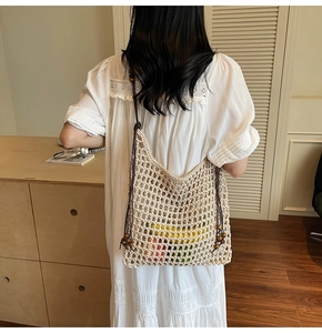 Detail of hollow-out straw woven tote bag with wooden beads and slim brown shoulder strap