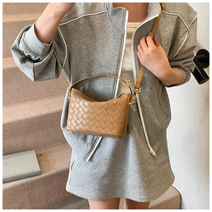 Detailed close-up of light brown woven leather crescent bag with adjustable strap