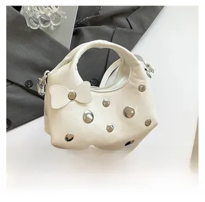 Detail of white PU leather cloud bag featuring silver studs and leather bow ornament
