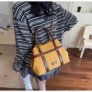 Détail du sac fourre-tout en toile jaune moutarde avec poignées et bandoulière en cuir brun