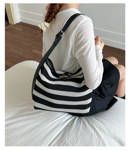 Detail of woven striped tote bag with leather strap and wooden toggle closure