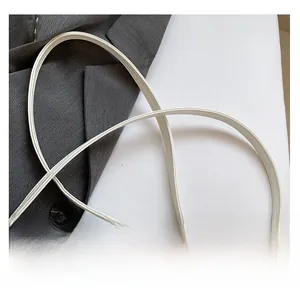 Close-up of white leather crescent bag featuring a slender adjustable shoulder strap