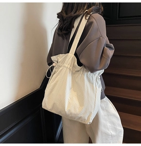 Dettaglio della borsa tote in nylon beige con chiusura a coulisse e trama trapuntata
