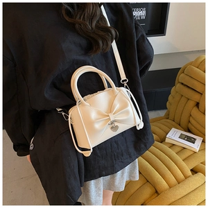 Détail d'un sac seau beige à nœud papillon et pendentif cœur sur une chaise chic