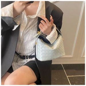 Detail of light blue woven leather handbag with intricate texture and gold zipper hardware