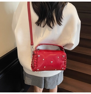 Detail of red PU leather bag with silver heart rivets and pleated edge on stairs