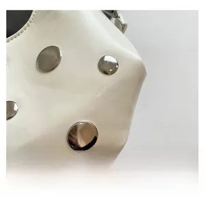 Close-up of premium white leather texture and large silver metal rivets on the crescent bag