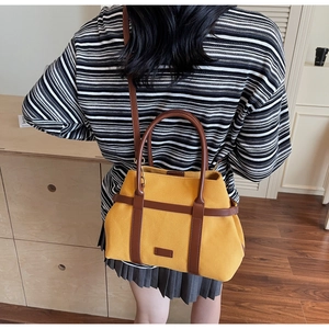 Détail du sac seau en toile jaune gingembre avec garniture en cuir et poignées rondes