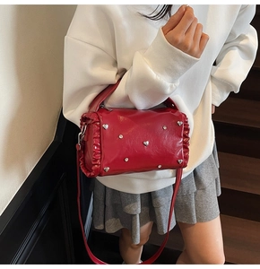 Macro detail of red glossy bag with silver heart studs and pleated side texture