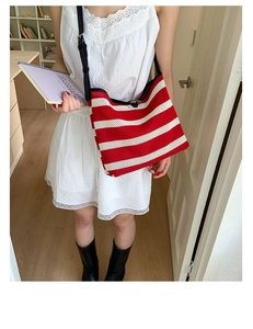 Détail du sac tricoté à rayures rouges et blanches avec bandoulière en cuir noir et maille