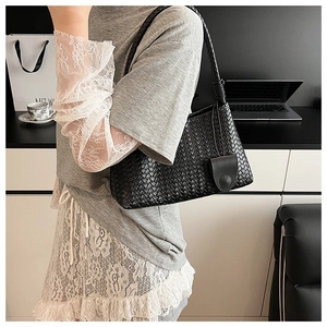 Close-up of black woven leather handbag showing intricate cross-knit texture and detail