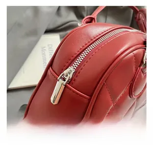 Macro shot of silver metal zipper on red quilted leather bag with diamond stitching
