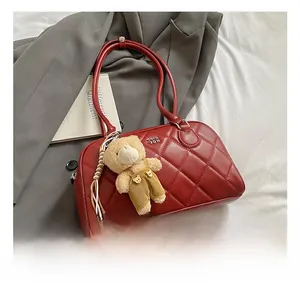 Detail of red quilted tote bag with diamond pattern and a cute plush bear charm accessory