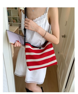 Close-up of red and white striped knit tote bag with black strap and wooden clasp details