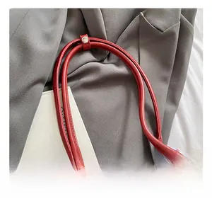 Close-up of red quilted leather handle with fine stitching on a trendy tote bag