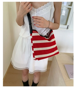 Detail of red and white striped crochet knit tote bag with black leather shoulder strap
