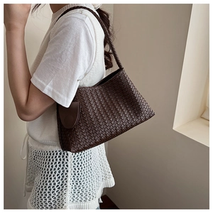 Detail of the woven texture and shoulder strap on this dark brown hand-woven armpit bag