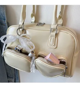 Detail of cream white leather bag with lace bow, pearls and dual front zipper pockets