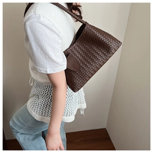 Macro shot of dark brown hand-woven leather texture on a high-end shoulder bucket bag