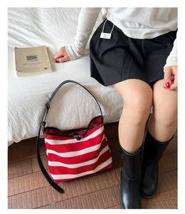 Détail du sac cabas tissé à rayures rouges et blanches avec sangle noire et bouton corne