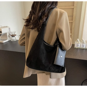 Detail of black suede hobo tote bag with matching small pouch in a cozy cafe setting