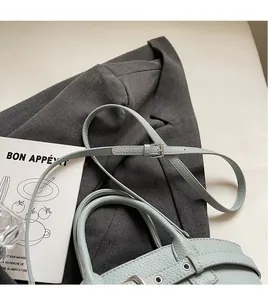 Detail of light blue lychee pattern leather bag with silver buckle and adjustable strap