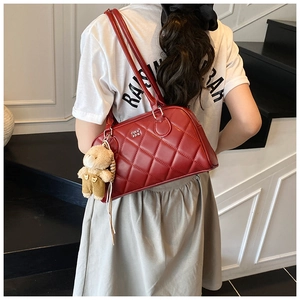 Detail of red quilted tote bag with cute brown bear charm on a black staircase