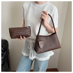 Detail of dark brown woven leather shoulder bag with matching zipper pouch on a chair