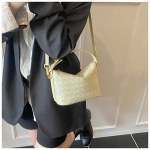 Detail of light beige woven leather handbag with gold metal hardware on model