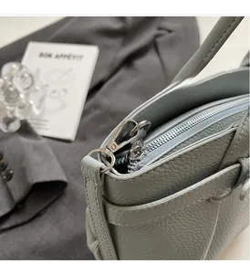 Detailed close-up of premium lychee grain leather and silver metal hardware on a bucket bag