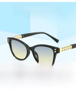 Detail of square cat-eye sunglasses featuring golden chain temples and gradient lenses
