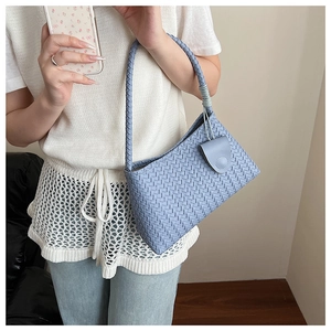 Close-up of light blue Intrecciato woven texture and magnetic flap closure on handbag