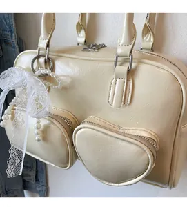 Detail of cream bowling bag with heart zipper pockets and pearl lace bow charm