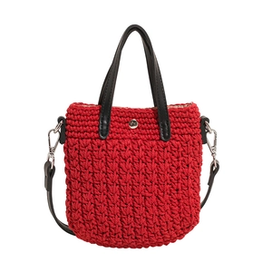 Détail d'un sac à main tressé rouge avec anses en cuir noir et fermoir argenté chic