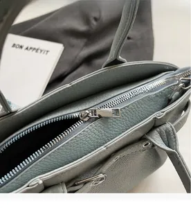 Close-up of a smooth silver zipper on a blue lychee pattern leather handbag detail