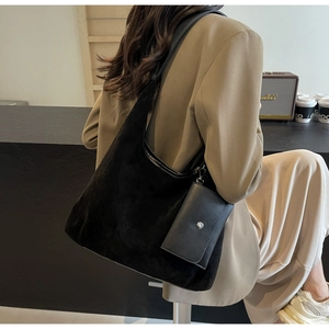Large black suede tote bag with matching small pouch shown in stylish cafe setting