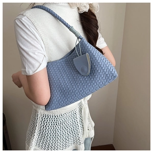 Detail of light blue woven leather shoulder bag with textured weave and round strap
