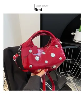Detail of red glossy patent leather handbag with silver studs and a decorative bow detail