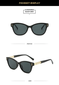 Detail view of black cat-eye sunglasses with luxury gold chain temples and grey lenses