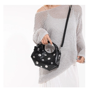 Detail of black patent leather shoulder bag with silver studs and a chic bow decoration