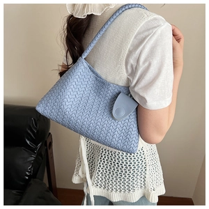 Detail of light blue woven texture and magnetic flap closure on the shoulder bag