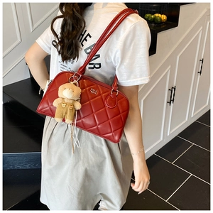 Close-up of red quilted tote bag with cute teddy bear charm and metal logo details