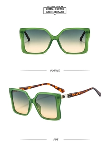 Detail of oversized square sunglasses with green frames and leopard print temples