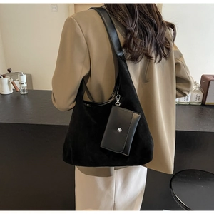Detail of black suede shoulder bag with leather trim and small pouch on a model