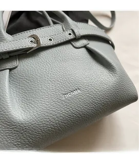 Close-up of litchi grain leather bucket bag with silver buckle and brand logo details
