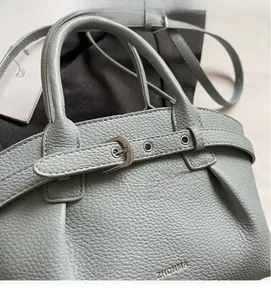 Close-up of light blue lychee pattern leather bag with buckle detail and brand logo