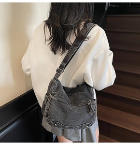 Detailed back view of a black washed denim crescent bag with studs on a street style model
