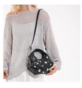 Close-up of black PU leather crescent bag with silver studs and a chic bow detail