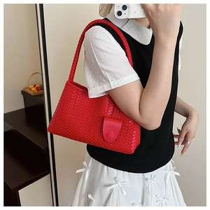 Close-up of red woven leather tote bag with classic weave texture and shoulder strap